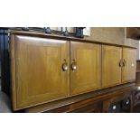 An Ercol medium elm wall cabinet enclosed by four rectangular doors with dished handles, together