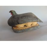 Softwood carving of a guinea fowl seated on eggs, 80cm