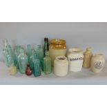 A collection of salt glazed jars together with further advertising bottles and other glass wares