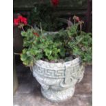 A pair of weathered cast composition stone garden urns of circular form with Greek key and grape