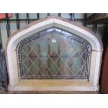 A reclaimed painted pine framed casement window of Gothic arched form enclosing a coloured leaded
