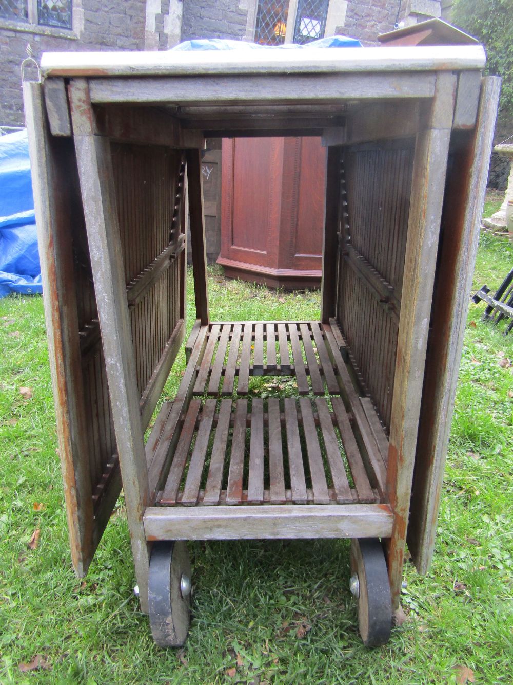 A weathered contemporary teak drop leaf garden table with slatted panelled top and moveable wheels - Image 2 of 2