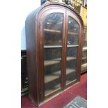 A 19th century pitch pine side cabinet of arched form enclosed by a pair of full length glazed