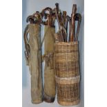 A large collection of mainly rustic walking sticks, two in a bag, the others in a wicker basket (
