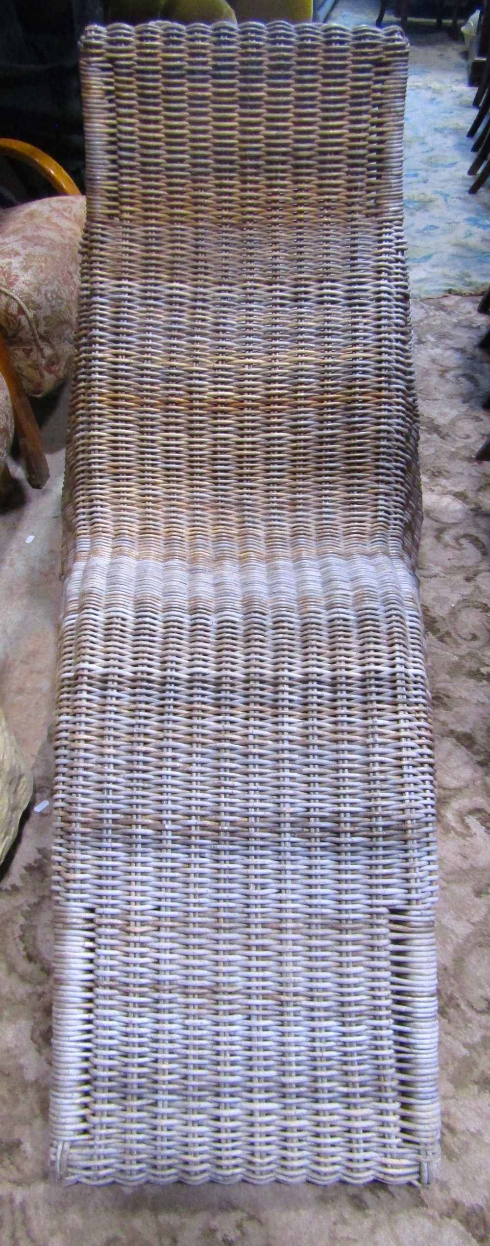 A wicker conservatory/garden lounger with shaped outline