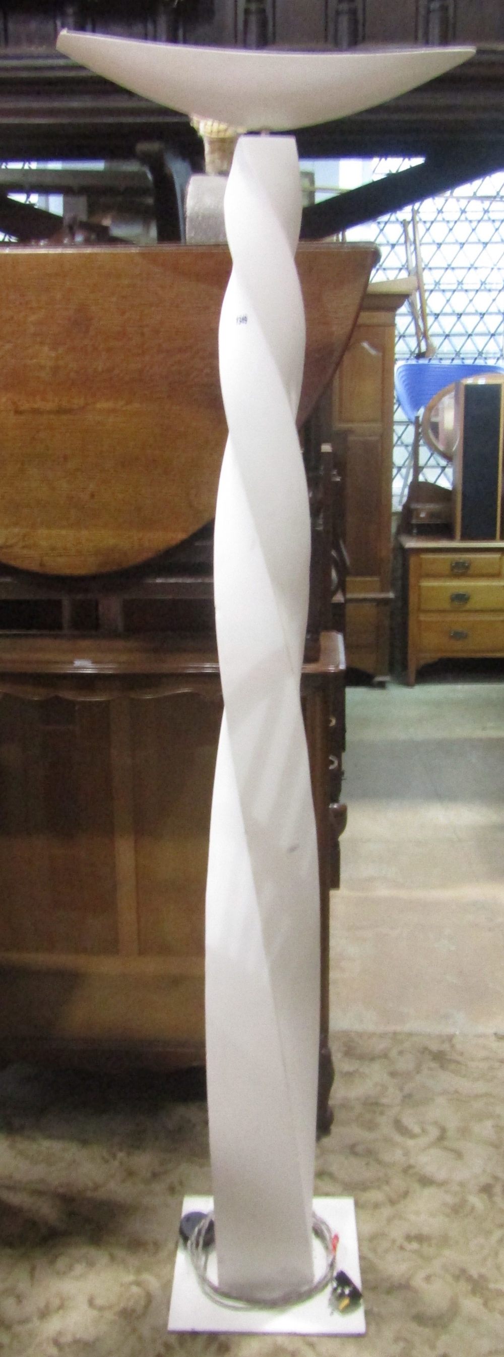 A contemporary floorstanding uplighter with sculptural twisted plaster column raised on a square