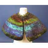 An elaborate shoulder shawl/shrug decorated with extensive bands of feathers in iridescent