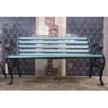 A three seat garden bench with green painted timber lathes raised on a pair of cast iron end