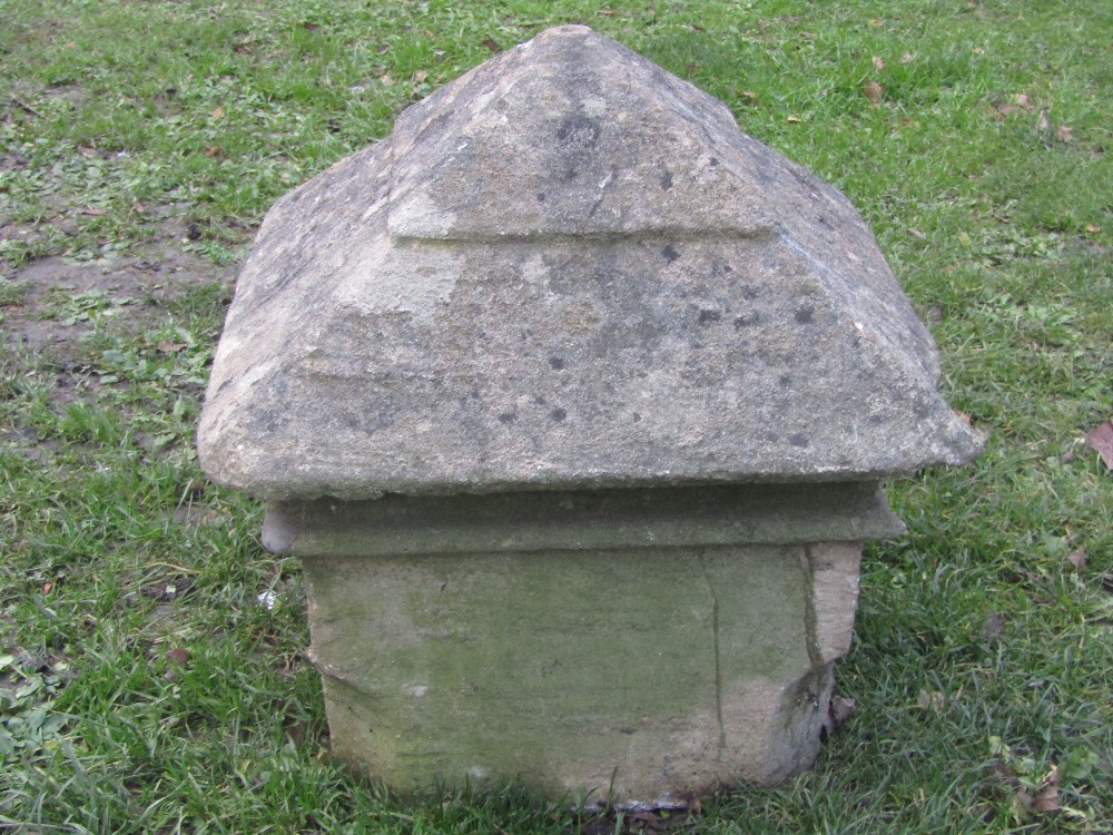 A weathered carved natural stone pillar cap of square form with stepped pyramid top