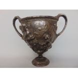 A 19th century high relief cast metal twin handled cup, with silvered finish decorated with