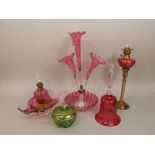 A collection of Cranberry glass to include a three pronged epergne (AF), a bell, brass oil lamp with