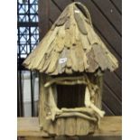 A decorative rustic hanging bird house of driftwood construction with conical shaped roof