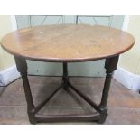 A rustic oak cricket table, the circular top raised on three gun barrel supports, the top 75cm