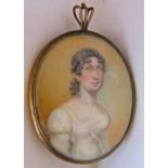 An early 19th century miniature portrait of oval form showing a woman in white dress, in circular
