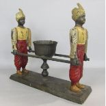 Novelty cast iron candlestick in the form of two blackamoors carrying a sedan carriage, 26cm long