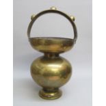 BRASS BALUSTER SHAPED VESSEL ON A SMALL PEDESTAL FOOT WITH HOOP HANDLE ORNAMENTED BY THREE APPLIED