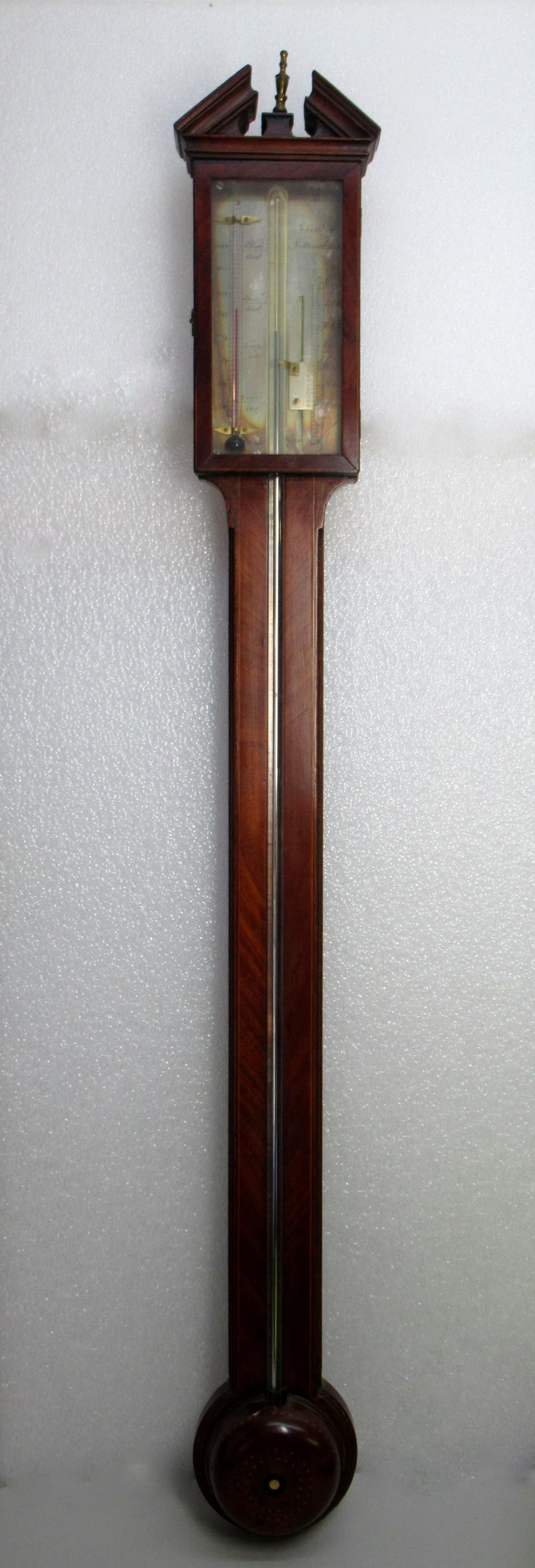 GEORGIAN MAHOGANY STICK BAROMETER WITH A BROKEN ARCH PEDIMENT ABOVE A GLAZED DOOR, THE SILVERED