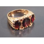 9ct GOLD RING SET THREE x 8mm OVAL CUT GARNETS AND FOUR SMALL GARNETS, SIZE N (4.3g GROSS)