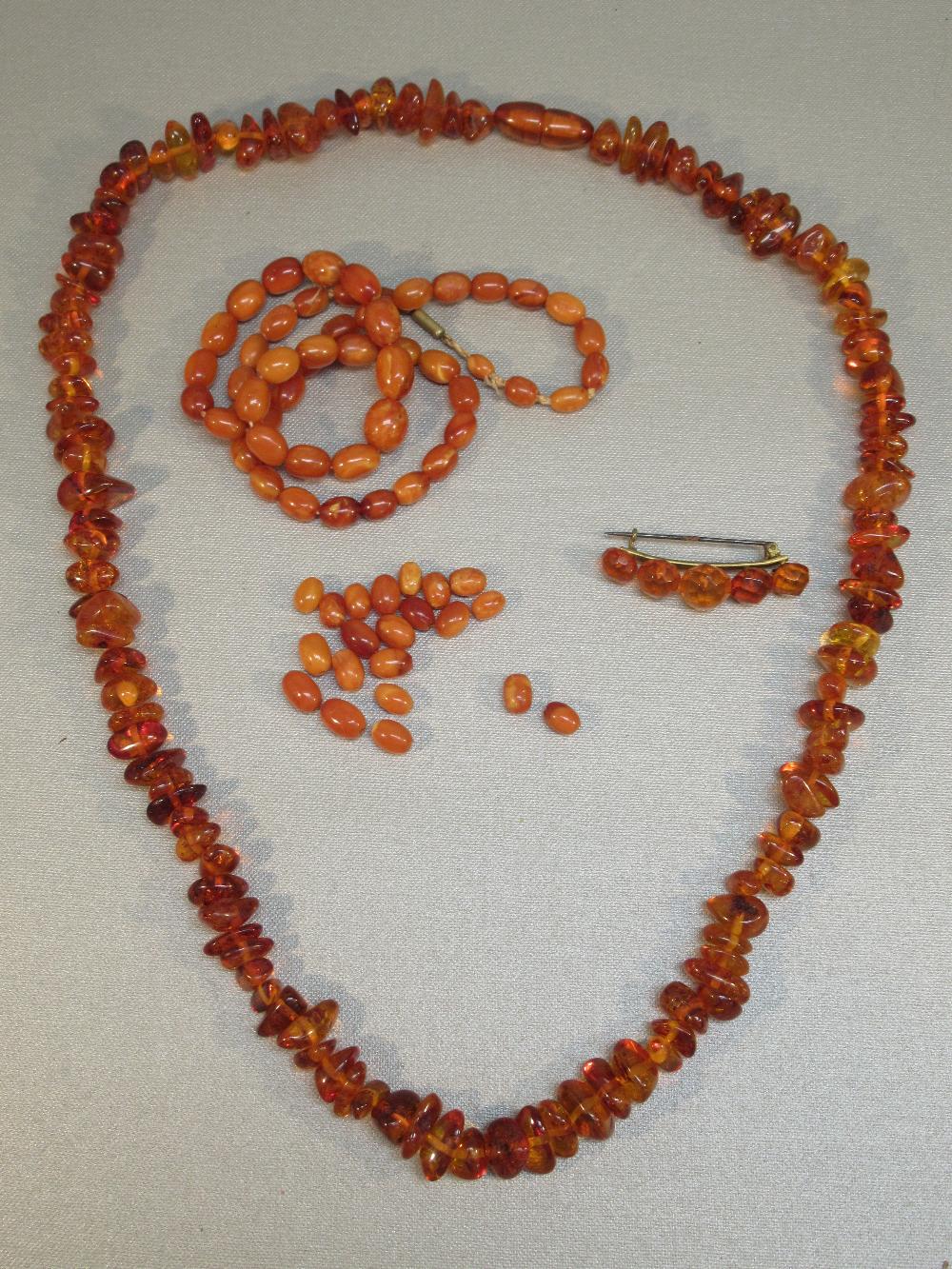 BAROQUE AMBER BEAD NECKLACE,LENGTH 61cm (41.8g) AMBER COLOURED BEAD NECKLACE AND A BROOCH [3]