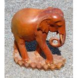 CARVED WOOD MODEL OF AN ELEPHANT STANDING ON A SHAPED BASE (H: 48cm x 44cm x 21cm) AND A COMPOSITION