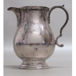 HEAVY GUAGE GEORGE III STYLE BALUSTER CREAM JUG WITH A SCROLL HANDLE, ON A RAISED CIRCULAR FOOT,