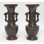 A PAIR OF JAPANESE BRONZE BALUSTER VASES WITH WINGED CREATURES IN RELIEF AND TWO SHAPED HANDLES,