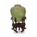 A green glazed pottery jar with a carved decor of fish. With later wooden stand. China, Tang. H. 6,5