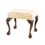 A GEORGE III MAHOGANY AND UPHOLSTERED STOOL the padded stuff-over seat on foliate carved cabriole