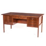 A BURMESE TEAK DESK DESIGNED BY ARNE VODDER the rectangular top centred by a drawer flanked by three