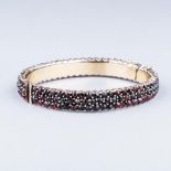 A BOHEMIAN GARNET BANGLE, LATE 19TH CENTURY hinged bangle set with rose cut garnets in pinchbeck