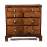 A GEORGE III WALNUT CHEST OF DRAWERS the hinged rectangular top enclosing an inset baize surface and