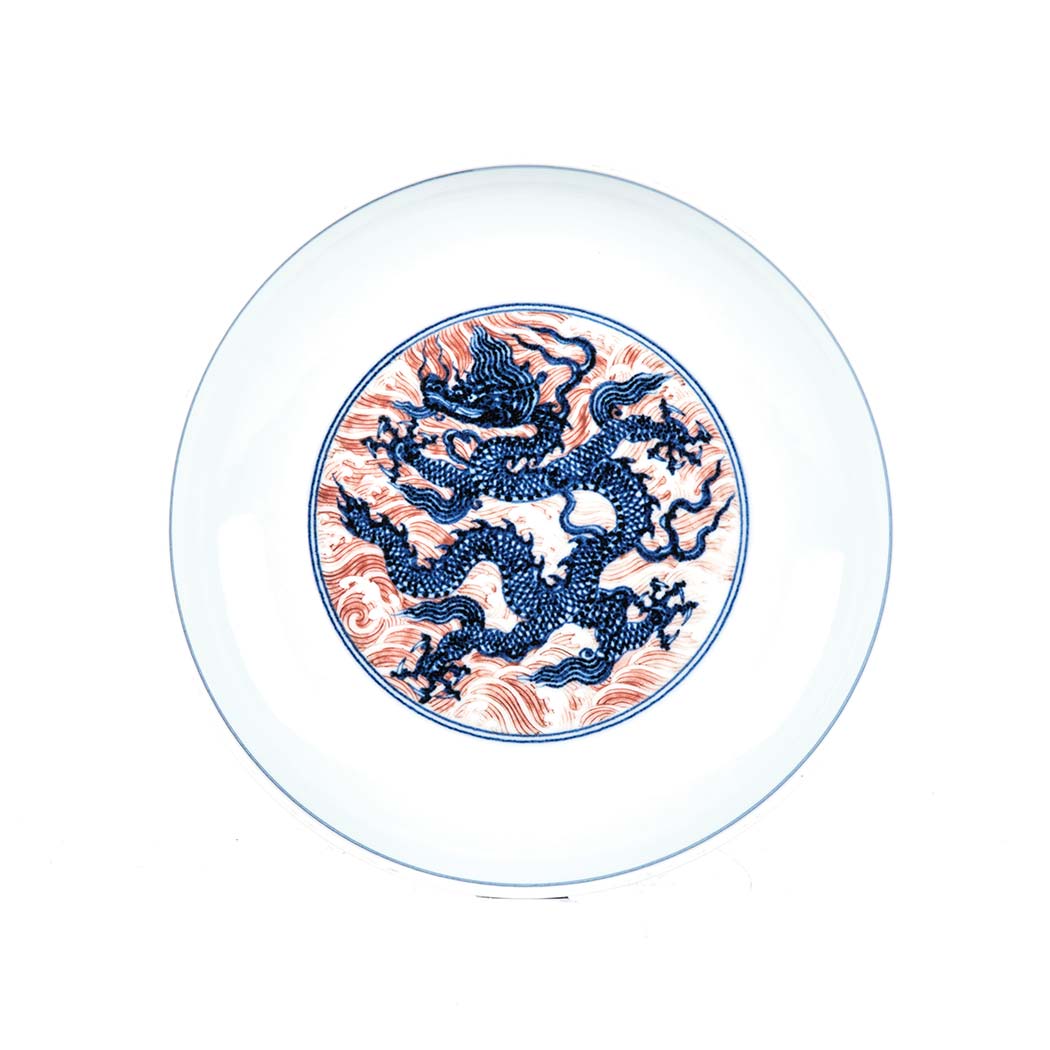 A CHINESE IRON-RED DECORATED BLUE AND WHITE ‘DRAGON’ SAUCER DISH decorated to the interior with an