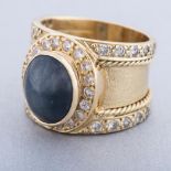 A STAR SAPPHIRE AND DIAMOND RING the broad tapered band bezel-set to the center with an oval