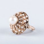 A VINTAGE GOLD AND PEARL DOME RING the done is centered by a pearl and is surrounded by a swirl of