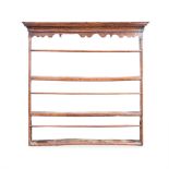 A GEORGE III OAK HANGING PLATE RACK the moulded outswept cornice above a plain frieze, three