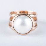 A MABE PEARL RING the central mabe pearl is tube set between three gold bands