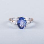 A TANZANITE AND DIAMOND RING the central oval cut tanzanite is flanked by trilliant cut diamonds