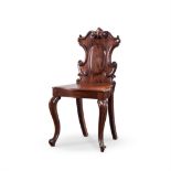 A MAHOGANY HALL CHAIR, 19TH CENTURY the curved top rail centred by a scroll crest, solid back, plank