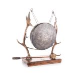 A DEER ANTLER GONG, EARLY 20TH CENTURY the circular metal gong suspended on chains flanked by