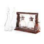 A TANTALUS WITH TWO GLASS DECANTERS the decanters etched with vine leaves throughout, with metal
