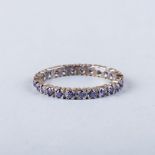 AN AMETHYST FULL ETERNITY RING of typical form, claw set with a single sapphire