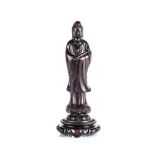 A CHINESE CARVED AND EBONISED HARDWOOD FIGURE OF GUANYIN standing on a double-lotus base,