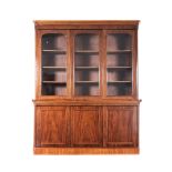 A VICTORIAN MAHOGANY BOOKCASE in two parts, the outswept cornice above a plain frieze, three