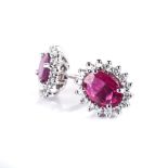 A PAIR OF RUBY AND DIAMOND EARRINGS each centred with an oval mixed-cut ruby weighing