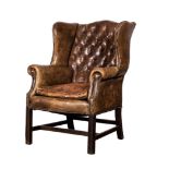 A LEATHER UPHOLSTERED WINGBACK ARMCHAIR, EARLY 20TH CENTURY the button back between close-nailed