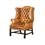 A LEATHER UPHOLSTERED WINGBACK ARMCHAIR, 20TH CENTURY the button back between close-nailed sides,
