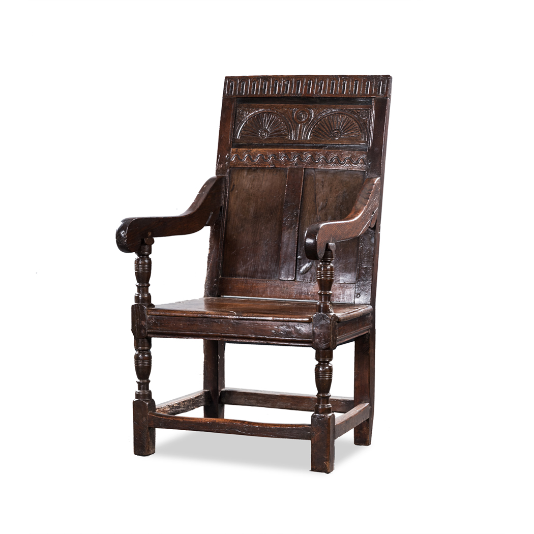 AN OAK ARMCHAIR, 18TH CENTURY the carved and panelled back between curved arms on turned tapering