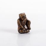 A JAPANESE FAUX HORN NETSUKE OF AN ONI, TAISHO PERIOD, 1912 – 1926 the seated figure dressed in a