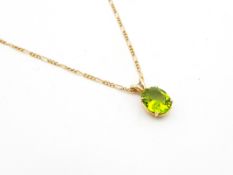 A single stone peridot pendant, oval cut peridot measuring 11.5 x 9.4mm, mounted in 9ct yellow