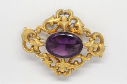 Large brooch, set with an oval purple stone, in an openwork gilt frame, measures approximately 68